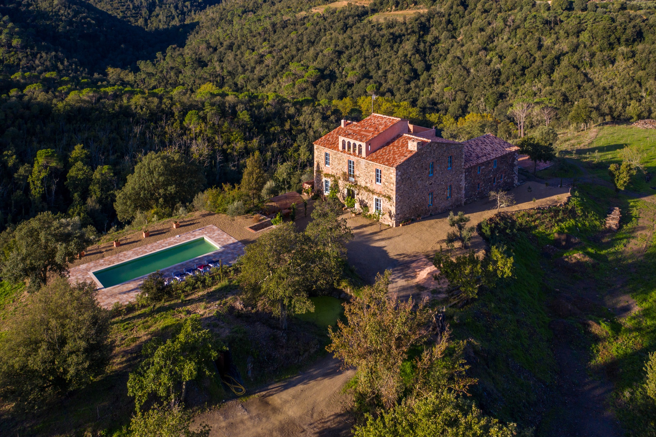 Masia de pedra amb piscina envoltada de bosc